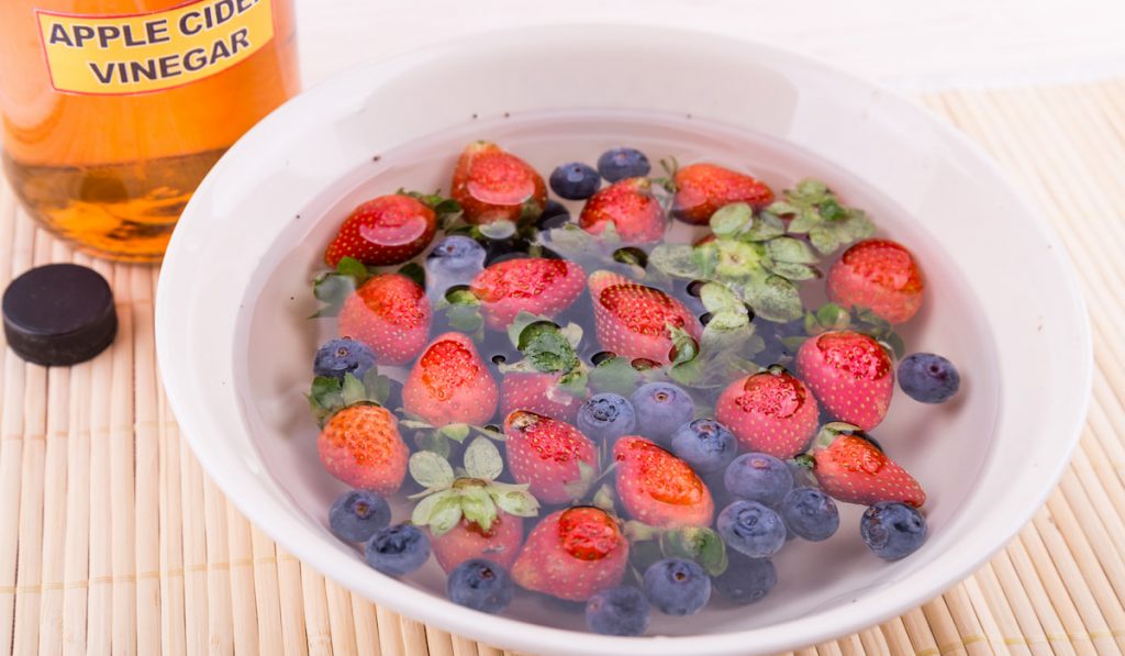 Washing berries in a bowl using water and vinegar
